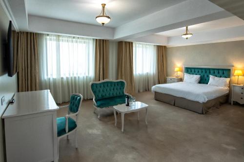 ルーマンにあるHotel Roman by Dumbrava Business Resortのベッド、テーブル、椅子が備わるホテルルームです。
