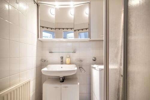 een witte badkamer met een wastafel en een spiegel bij Cozy Central Flat Spittelberg in Wenen
