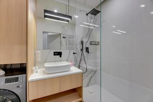a bathroom with a shower and a sink and a washing machine at Apartments Doki by TriApart in Gdańsk