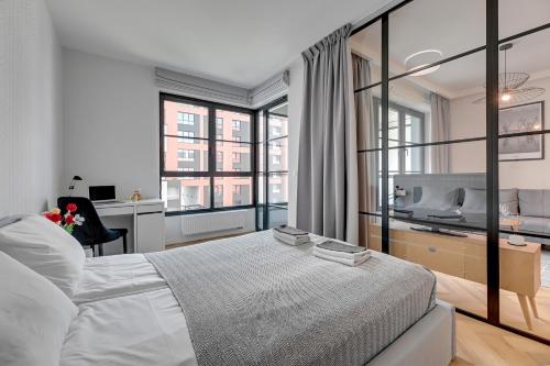 a bedroom with a large white bed and a desk at Apartments Doki by TriApart in Gdańsk