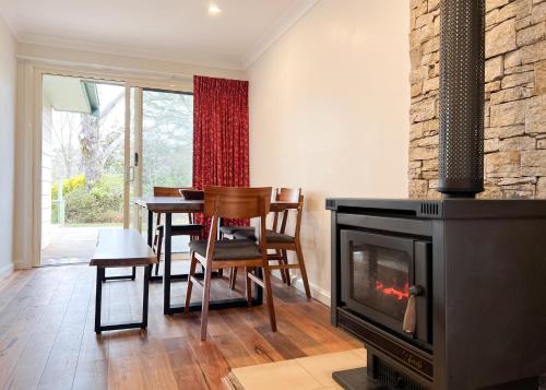 a living room with a fireplace and a table and chairs at Birdwood Guesthouse in Blackheath