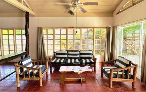 ein Wohnzimmer mit einem Sofa, Stühlen und Fenstern in der Unterkunft White House, Batangas in Lian
