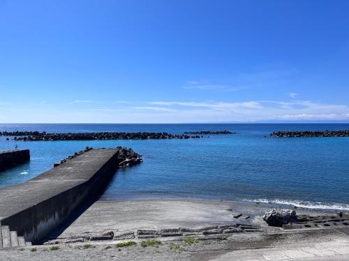 ein Pier im Ozean mit Felsen im Wasser in der Unterkunft Etcetera Guest House in Niijimamura