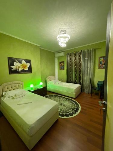 2 Betten in einem Zimmer mit grünen Wänden in der Unterkunft Bora Hotel in Gjirokastër