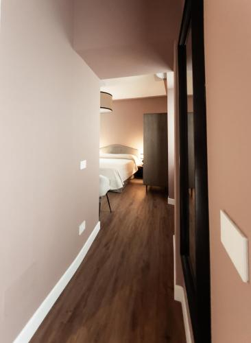 a hallway with a bedroom and a bed in a room at Caffè delle Rose Les Chambres in Verbania