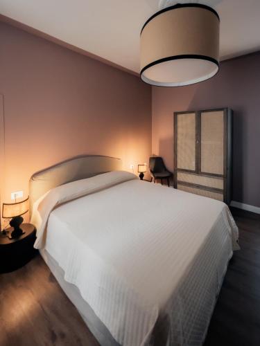 a bedroom with a large white bed and a lamp at Caffè delle Rose Les Chambres in Verbania
