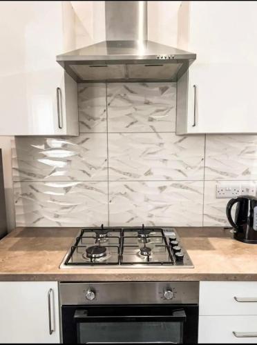 a stove top oven in a kitchen with white cabinets at Lovely 1-bedroom apartment, free street parking in Elswick