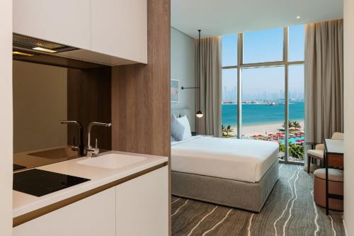 a hotel room with a bed and a view of the beach at Th8 Palm Dubai Beach Resort Vignette Collection, an IHG hotel in Dubai