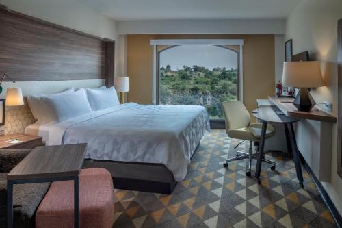 a hotel room with a bed and a desk and a window at Holiday Inn Tlaxcala by IHG in Tlaxcala de Xicohténcatl