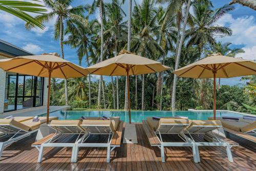 a deck with chairs and umbrellas next to a swimming pool at Brand NEW 6BR Villa Amazing VIEWS in Ubud