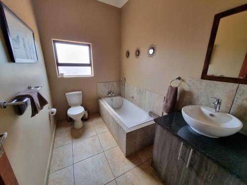 La salle de bains est pourvue d'un lavabo, d'une baignoire et de toilettes. dans l'établissement Sondela Nature Reserve & Spa Chalets, à Bela-Bela