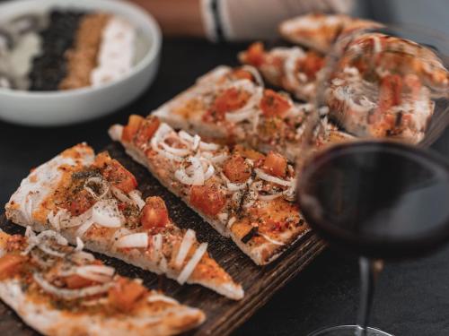 a table with a plate of pizza and a glass of wine at Venus Sunrise Suites & Villas in Vourvoulos