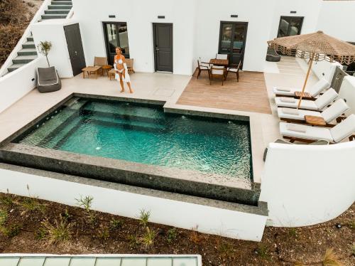 a woman standing next to a swimming pool in a house at Venus Sunrise Suites & Villas in Vourvoulos