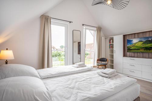 - une chambre blanche avec un grand lit et une fenêtre dans l'établissement WattWächter, à Büsum