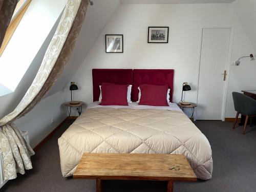 a bedroom with a large bed with a red headboard at La Ferme de la Place in Bouvines