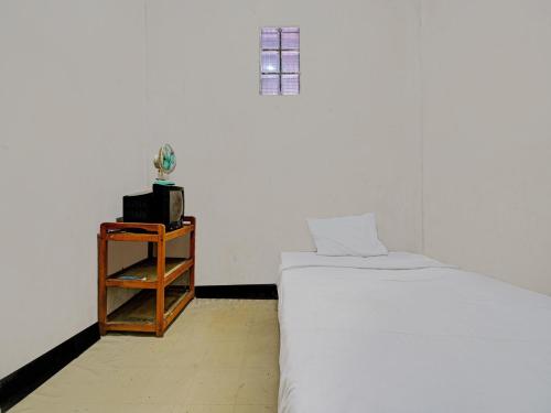 um quarto com uma cama e uma mesa de cabeceira ao lado de uma cama em OYO Life 92709 Kost Teras Cikapundung Syariah em Bandung