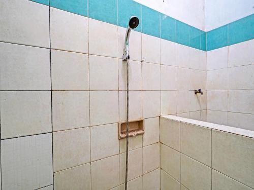 a shower with a hose in a tiled bathroom at OYO Life 92709 Kost Teras Cikapundung Syariah in Bandung