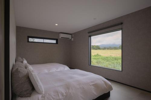 a bedroom with a white bed and a window at VACILANDO in Fujikawaguchiko