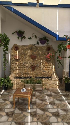 a stone wall with potted plants and a table at بيت العُمري (ام قيس) in Um Qeis