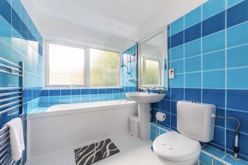 a blue tiled bathroom with a toilet and a sink at Peaceful Renovated 5BDR house wgarden in London