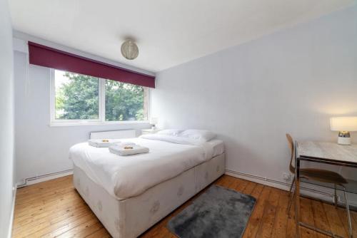 a white bedroom with a large bed and a desk at Peaceful Renovated 5BDR house wgarden in London