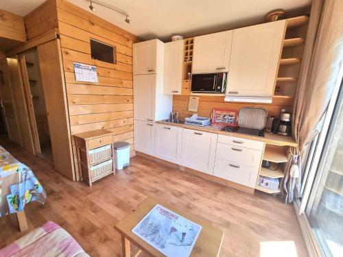 une cuisine avec des armoires blanches et un plancher en bois dans l'établissement Studio 4/6 pers., Chaillol 1600, proche ski/rando, balcon S/O, TV, lave-vaisselle, animaux ok. - FR-1-393-66, à Saint-Michel-de-Chaillol
