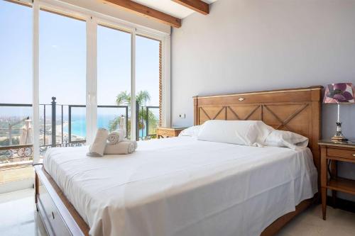 a bedroom with a large white bed with a large window at Vista Lara. Relájate y disfruta. in Nerja