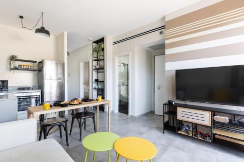 a living room with a table and chairs and a tv at Bright & Chic Apartment with Mamad in the City by Sea N' Rent in Tel Aviv