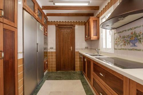a kitchen with wooden cabinets and a sink and a refrigerator at Vista Lara. Relájate y disfruta. in Nerja
