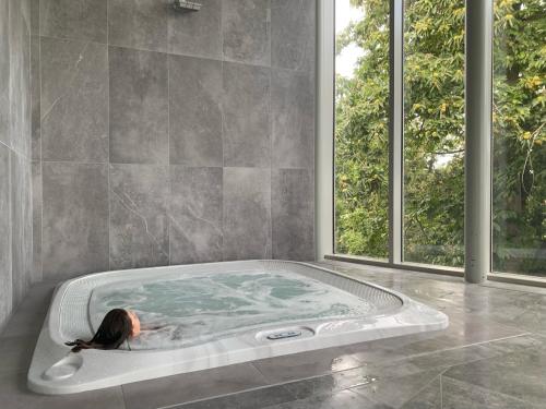 a woman laying in a hot tub in a bathroom at Le Lagon De Bréhec in Plouha