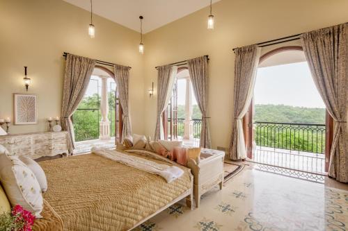 a bedroom with a bed and a balcony at LohonoStays Sacri Borod Hill 7 in Mandrem