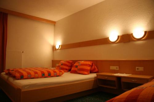 a bedroom with two beds with orange pillows and lights at Haus Alpina in Kaunertal