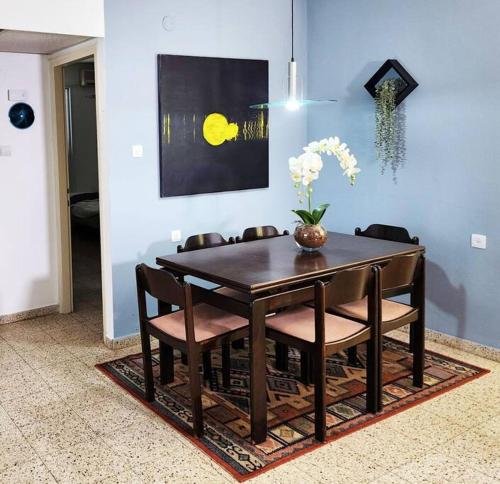 a dining room table with chairs and a vase with flowers at Spacious & Homely Retreat at the Diamond District in Tel Aviv