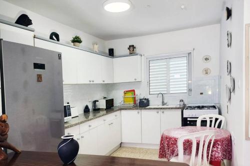 a kitchen with white cabinets and a refrigerator at Spacious & Homely Retreat at the Diamond District in Tel Aviv