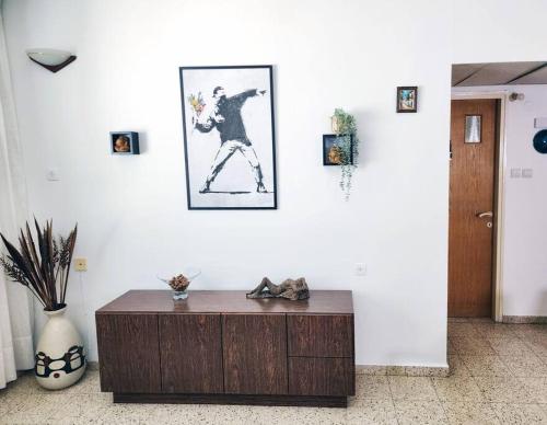 a living room with a table and a picture on the wall at Spacious & Homely Retreat at the Diamond District in Tel Aviv