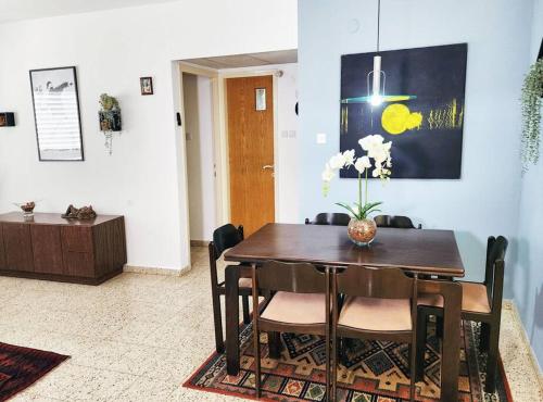 une table à manger avec des chaises et un vase de fleurs. dans l'établissement Spacious & Homely Retreat at the Diamond District, à Tel Aviv