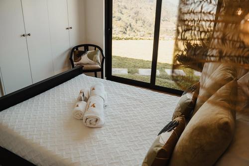 a bed with towels on it in a room with a window at Encosta de Louredo by Pousadela Village in Vieira do Minho