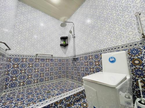uma casa de banho com WC e azulejos azuis e brancos em Mevlana Hotel em Samarkand