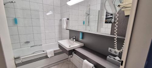 a bathroom with a sink and a mirror and a tub at Hotel Frankenland in Bad Kissingen