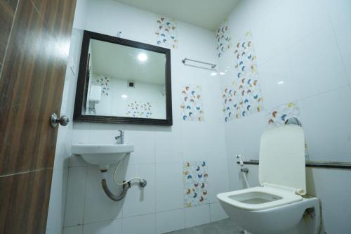 een badkamer met een toilet, een wastafel en een spiegel bij Hotel Anand in Kolhapur