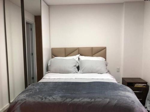 ein Schlafzimmer mit einem großen Bett mit weißer Bettwäsche und Kissen in der Unterkunft Studio Batel in Curitiba