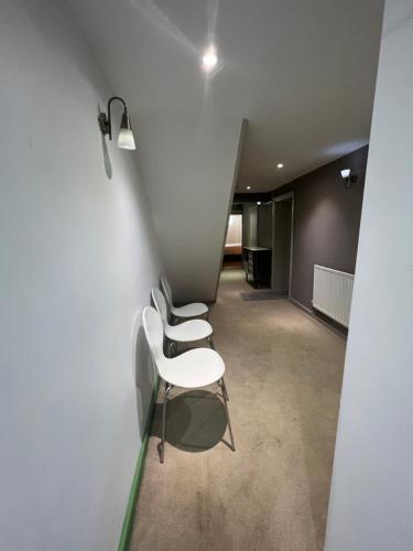 una fila di sedie bianche sedute in un corridoio di Spacious basement studio apartment a Manchester