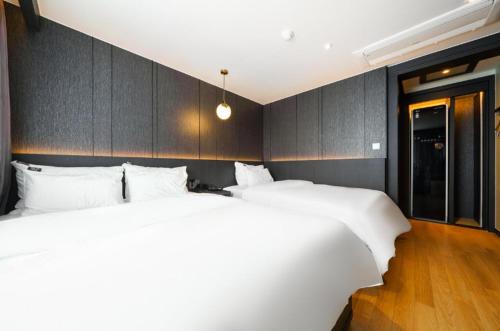 two beds in a hotel room with white sheets at STAY201 in Jecheon