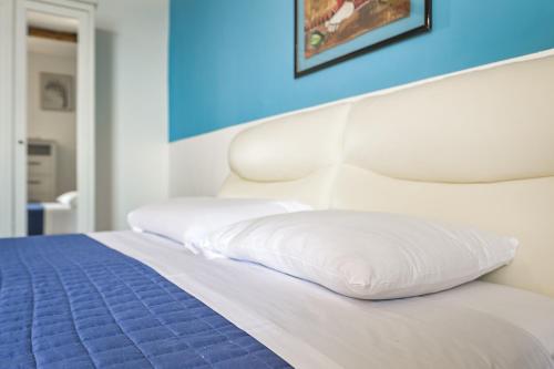 a bed with two white pillows and a blue wall at IL RIFUGIO SUL MARE - GenovaInRelax in Genova