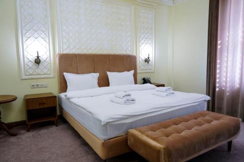 a bedroom with a large white bed and a stool at Sangzor Boutique Hotel in Samarkand