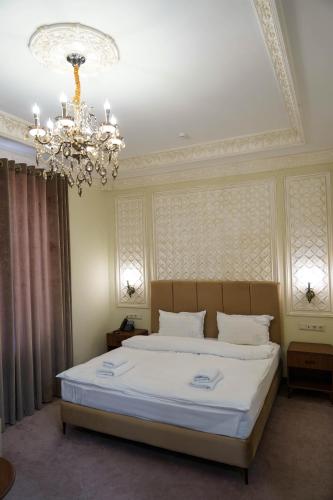 a bedroom with a large white bed with a chandelier at Sangzor Boutique Hotel in Samarkand