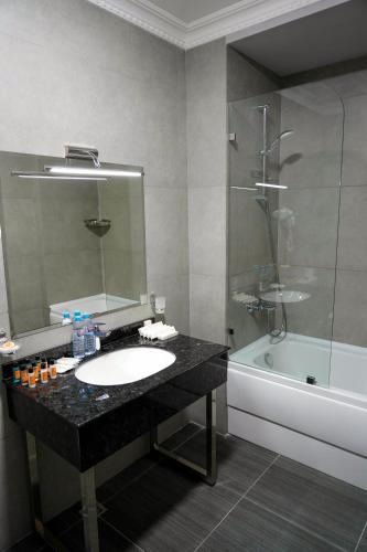 a bathroom with a sink and a mirror and a tub at Sangzor Boutique Hotel in Samarkand