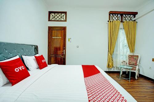a bedroom with a large bed with red pillows at Capital O 92990 Nena Kostel Syariah in Padang
