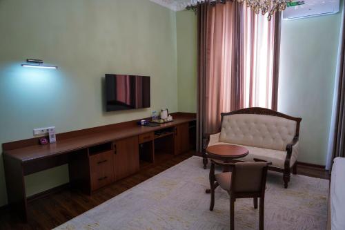 a living room with a couch and a desk with a television at Sangzor Boutique Hotel in Samarkand