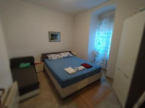 a small bedroom with a blue bed and a window at Aquamare Apartment in Rijeka